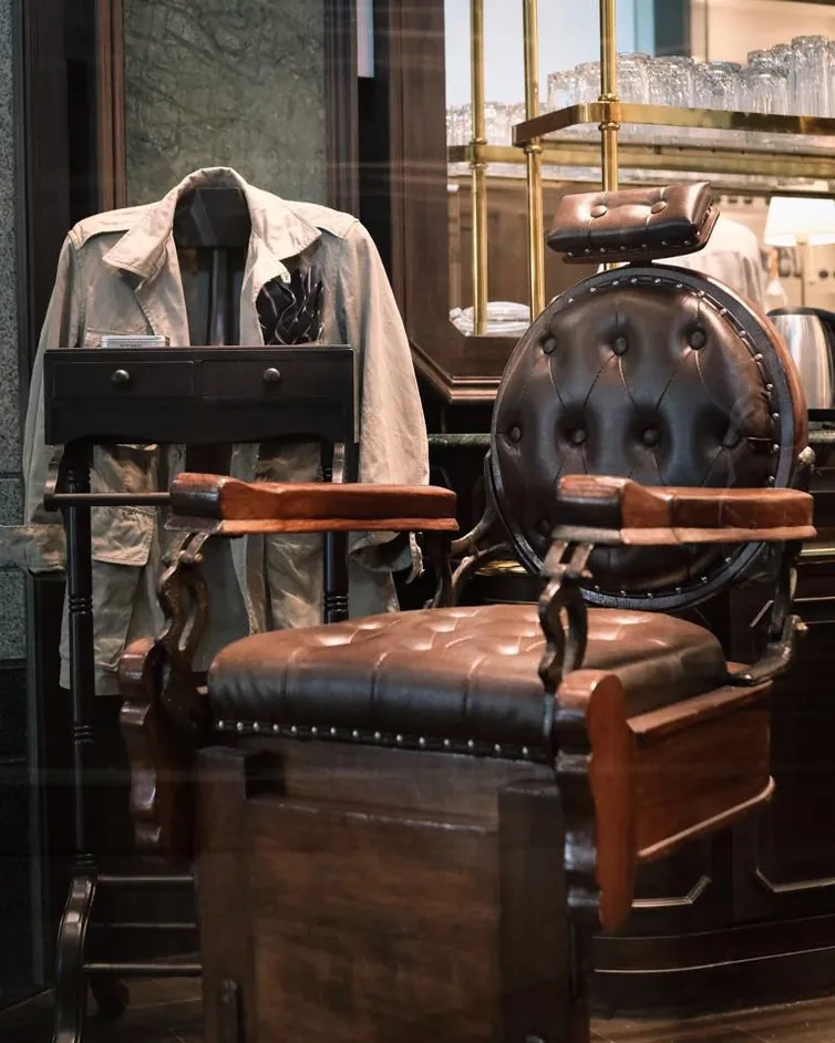 เก้าอี้ตัดผมหนังและแจ็กเก็ตแขวนอยู่ภายใน Black Amber Barber Shop and Tattoo