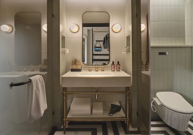 Bathroom vanity with a round mirror and globe lights at Public House Bangkok