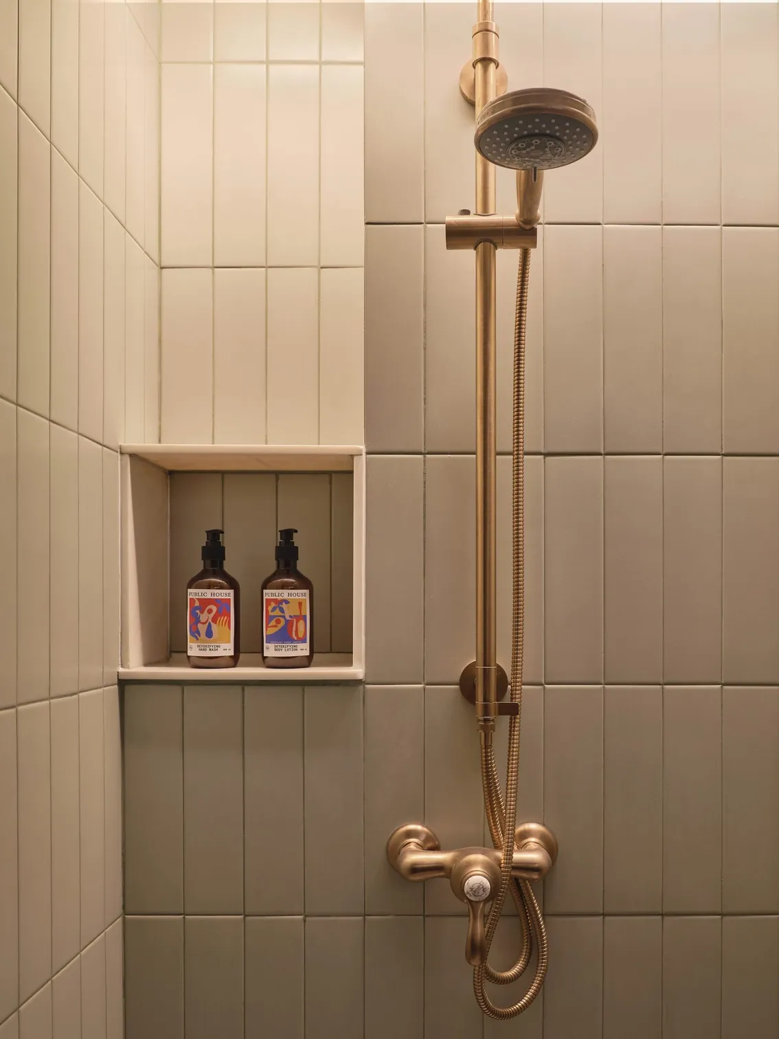 Tiled shower niche with brass fittings and bath amenities at Public House Bangkok
