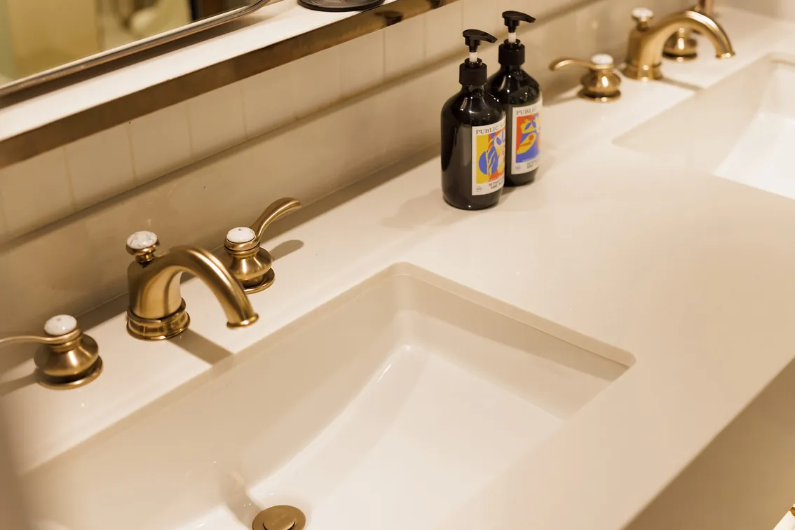 Twin basin with brass taps and Public House bath amenities in a One-Bedroom King Suite bathroom