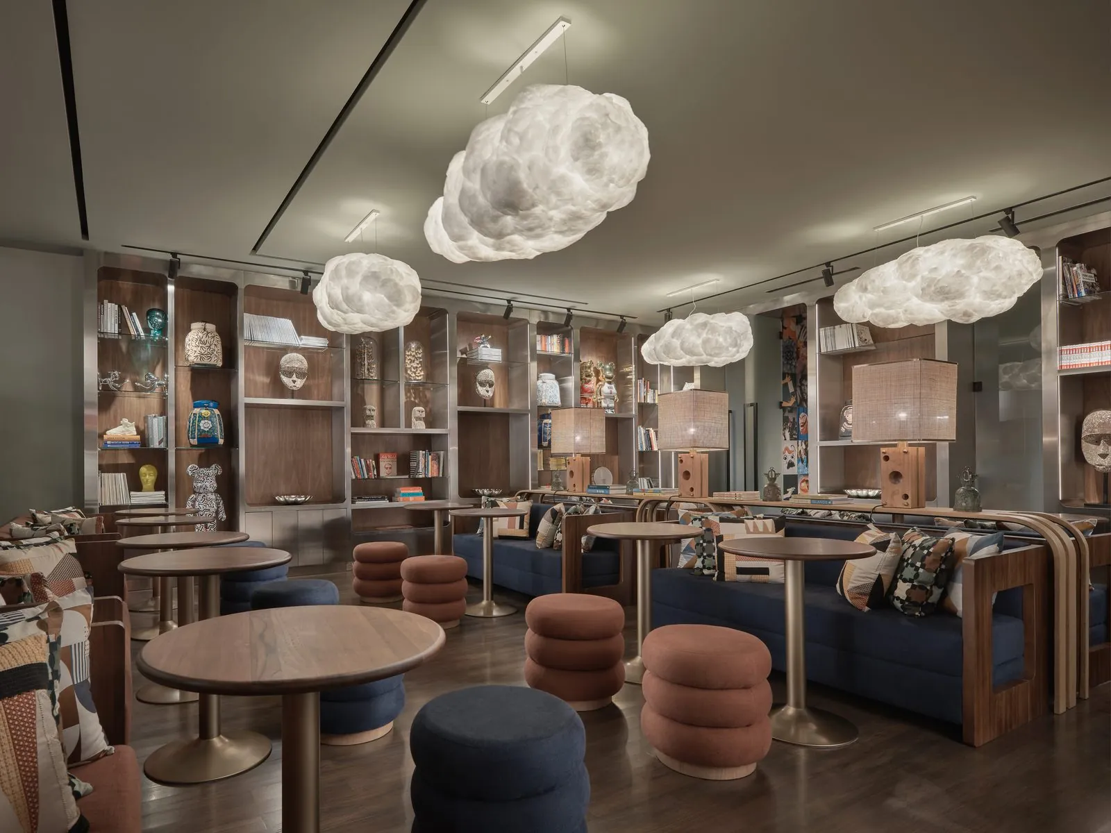 FORUM พื้นที่โคเวิร์กกิงที่ Public House Bangkok: โคมไฟรูปเมฆเหนือโต๊ะไม้กลม ที่นั่งยาวสีกรมท่า และชั้นวางหนังสือและเซรามิก