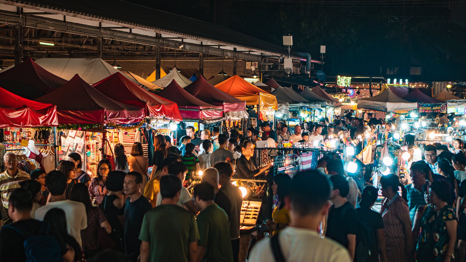 Crowds under the lit awnings of a Bangkok night market
