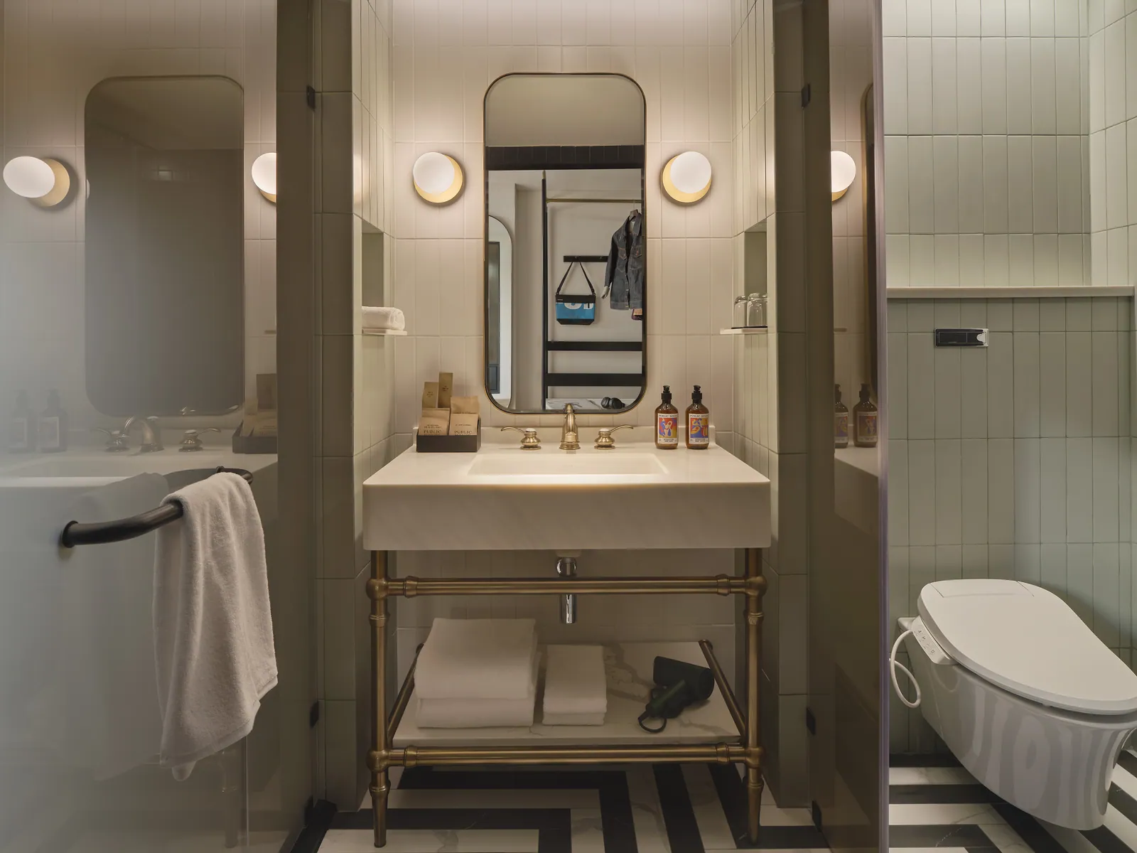 A guest bathroom at Public House Bangkok with a brass-fitted vanity and a deep bath