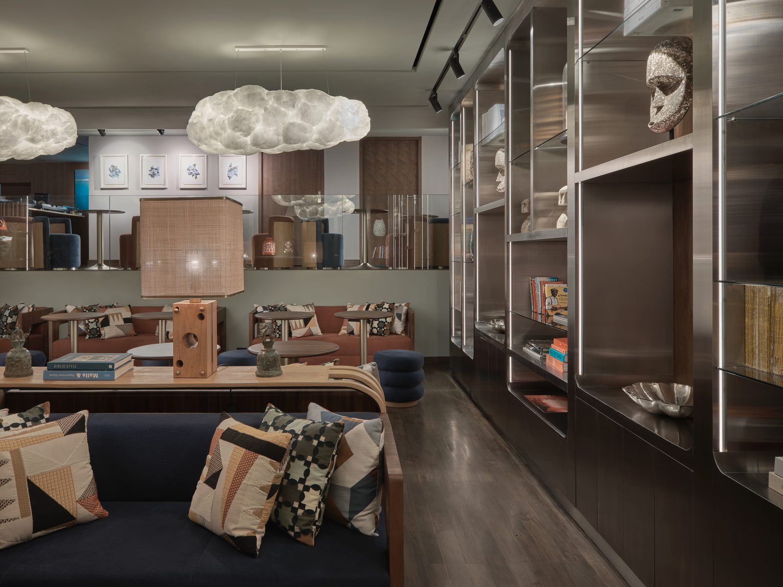 The lobby library at Public House Bangkok: books and objects on steel shelves beside banquette seating