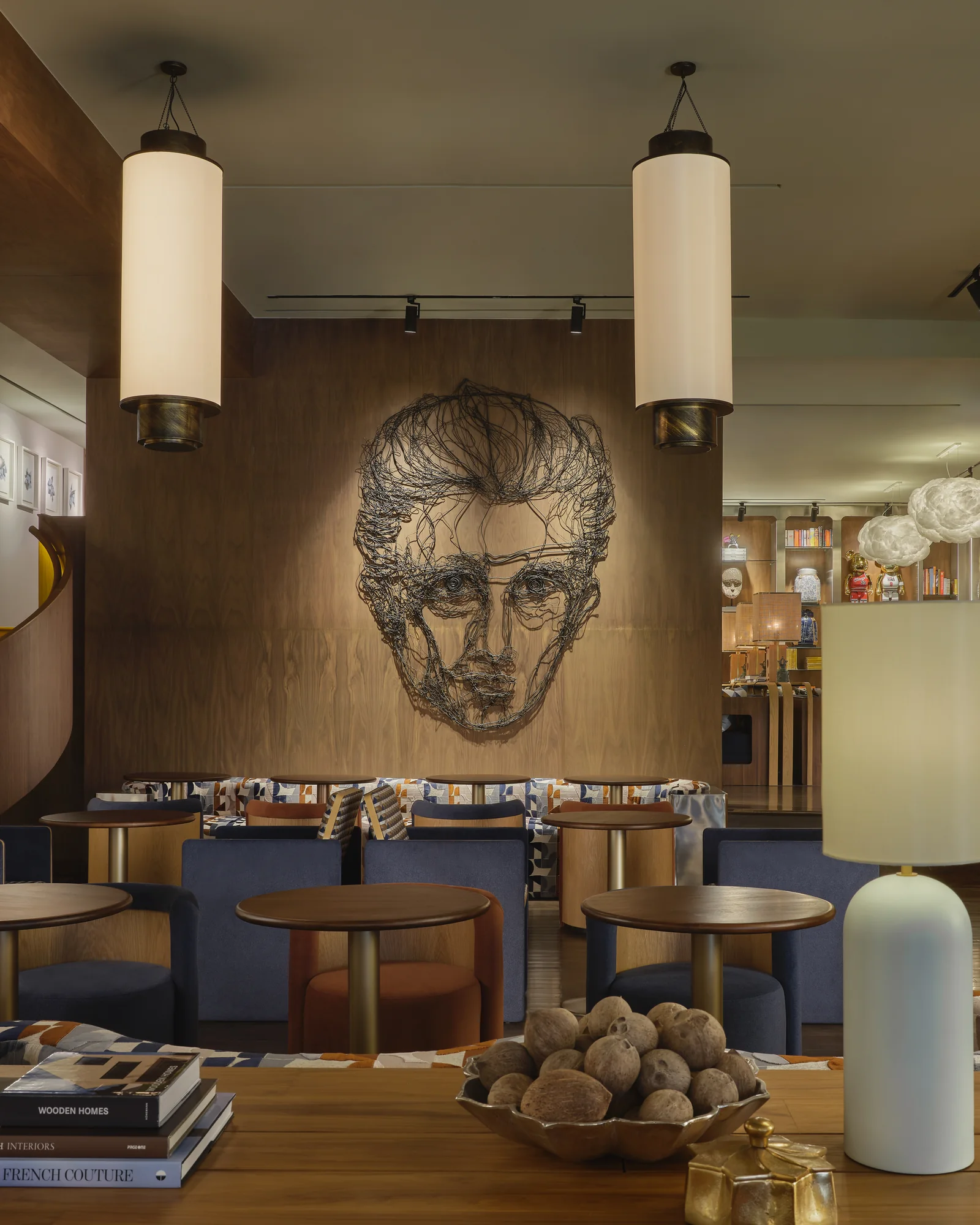 The bar lounge at Public House Bangkok, with a wire portrait above the banquettes and cylindrical pendant lights