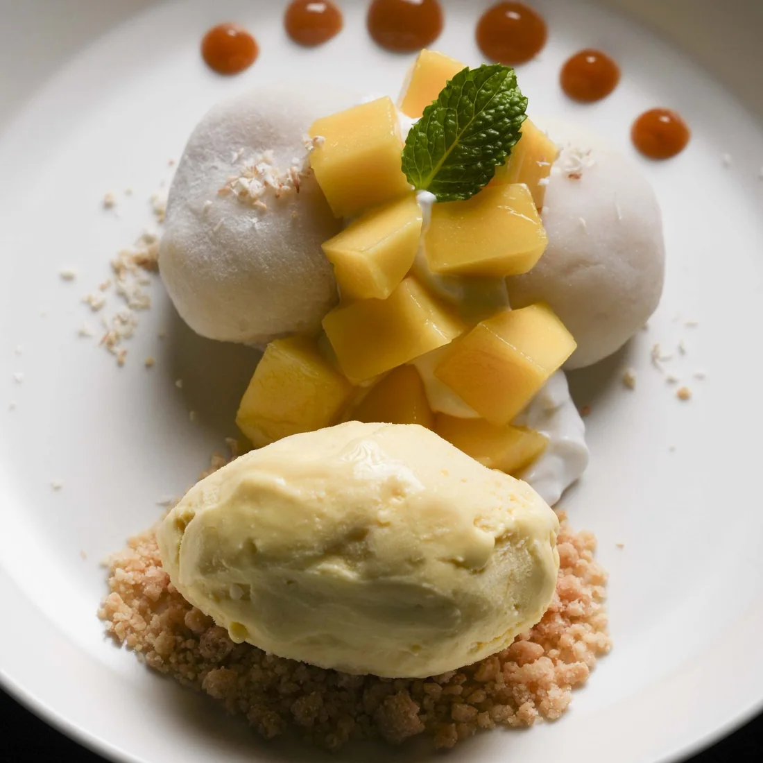 Mango sticky rice with mango sorbet, plated on a dark table at Public House Bangkok