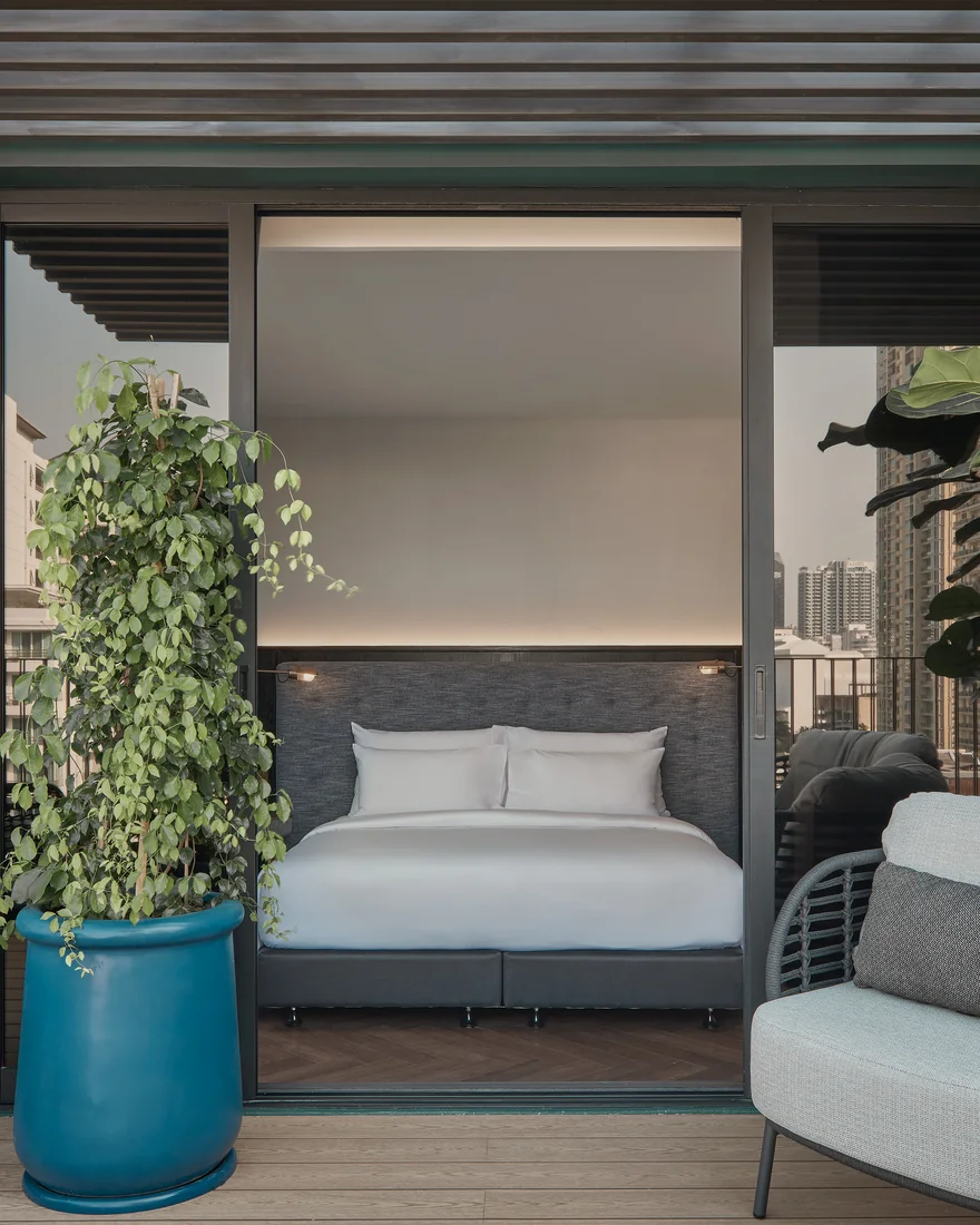 A guest room opening on to a planted balcony at Public House Bangkok