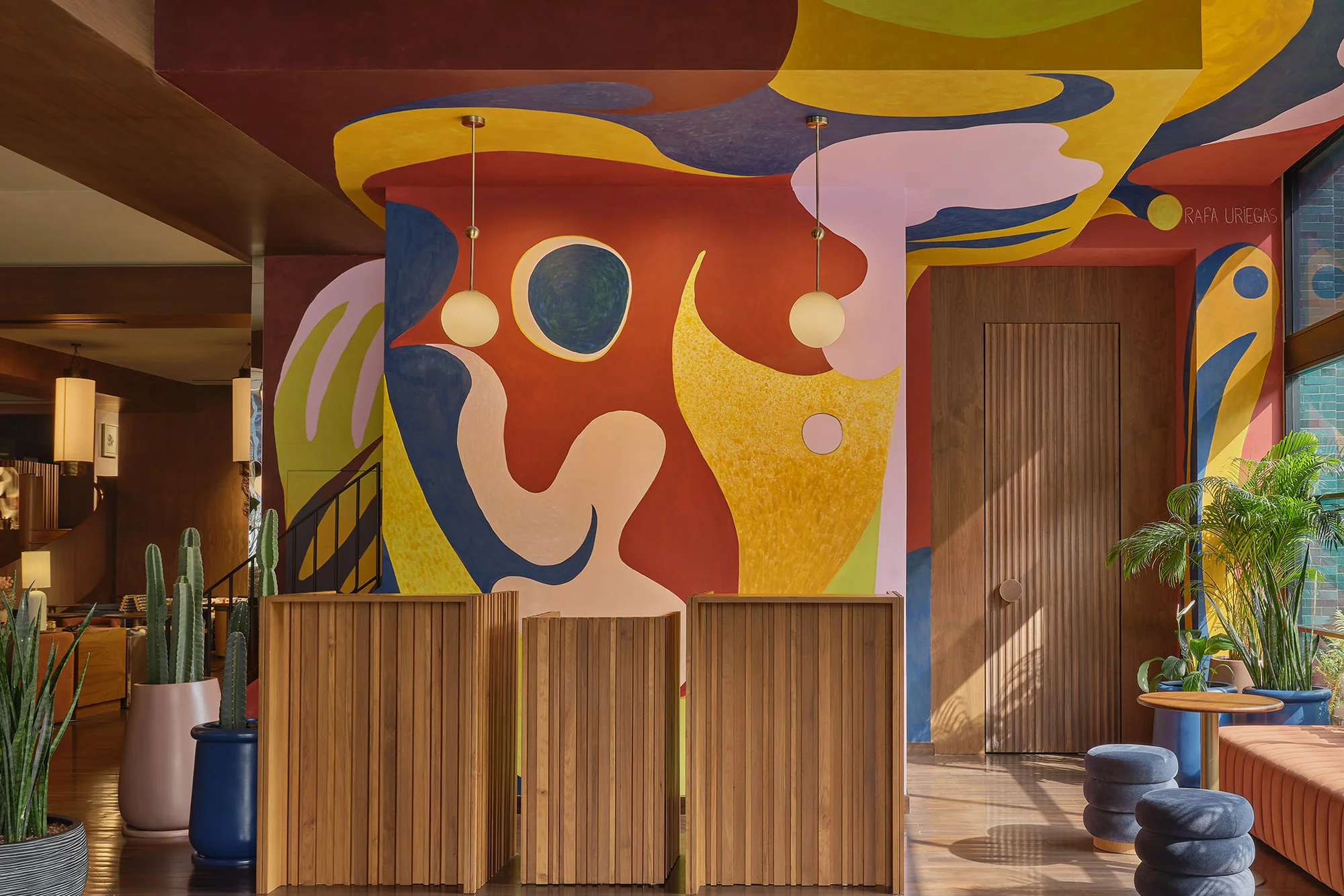 The painted mural wall in the lobby at Public House Bangkok, above timber joinery and blue seating