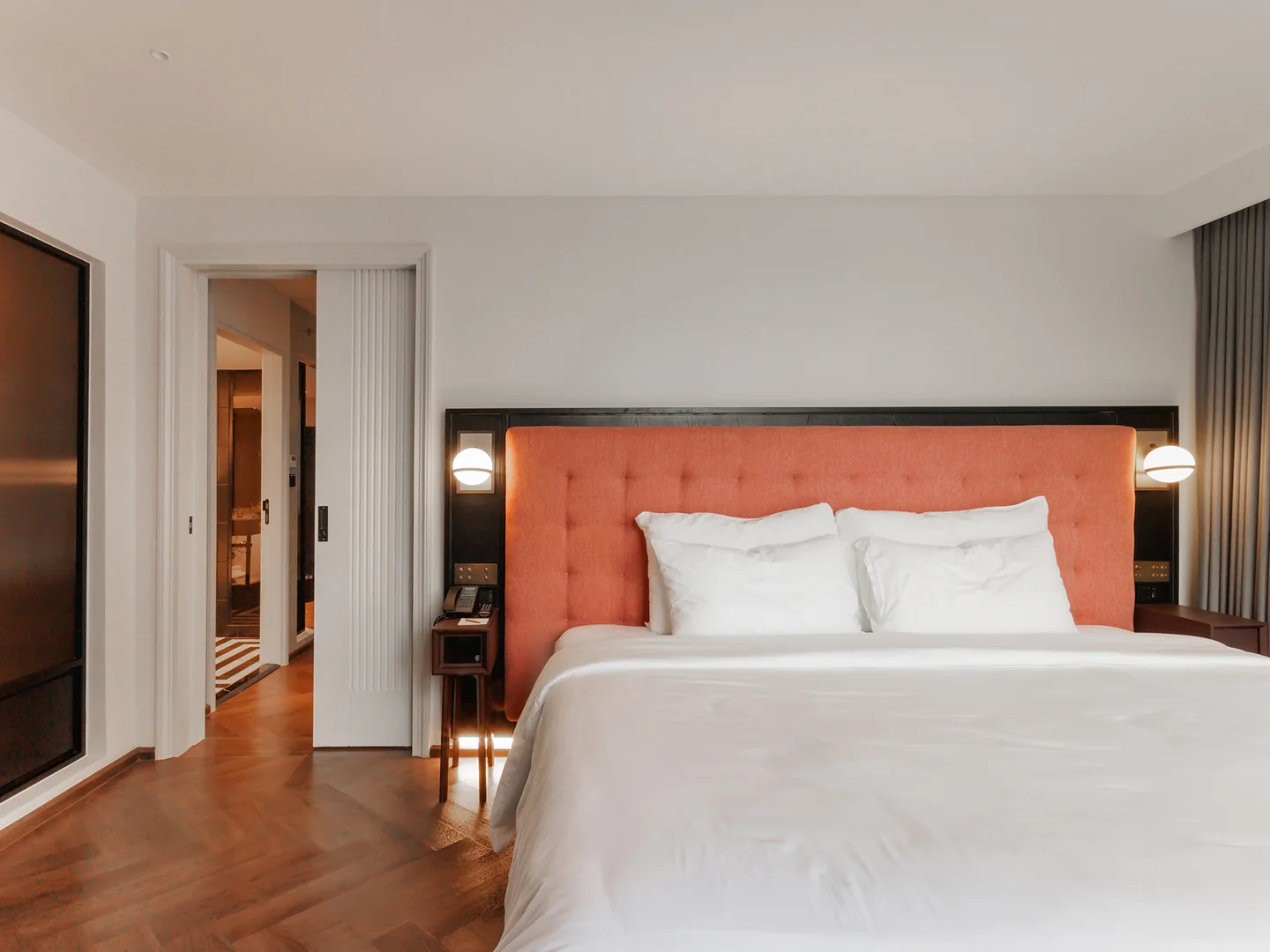 A bedroom in the 83 sqm Two-Bedroom Suite at Public House Bangkok, with the door open to the adjoining room