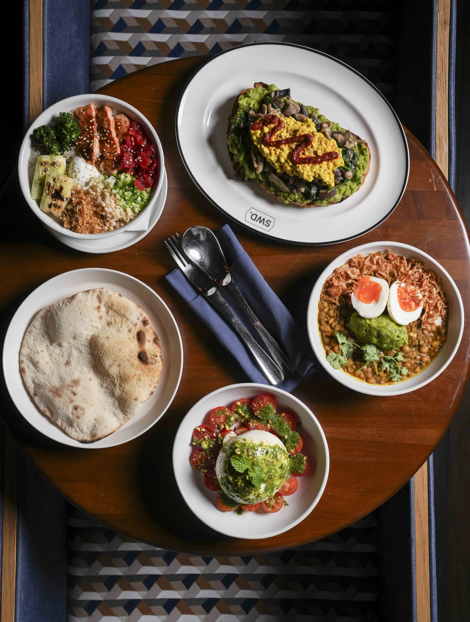 Bowls, a flatbread and coffee spread across a wooden table at SWD, the restaurant at Public House Bangkok